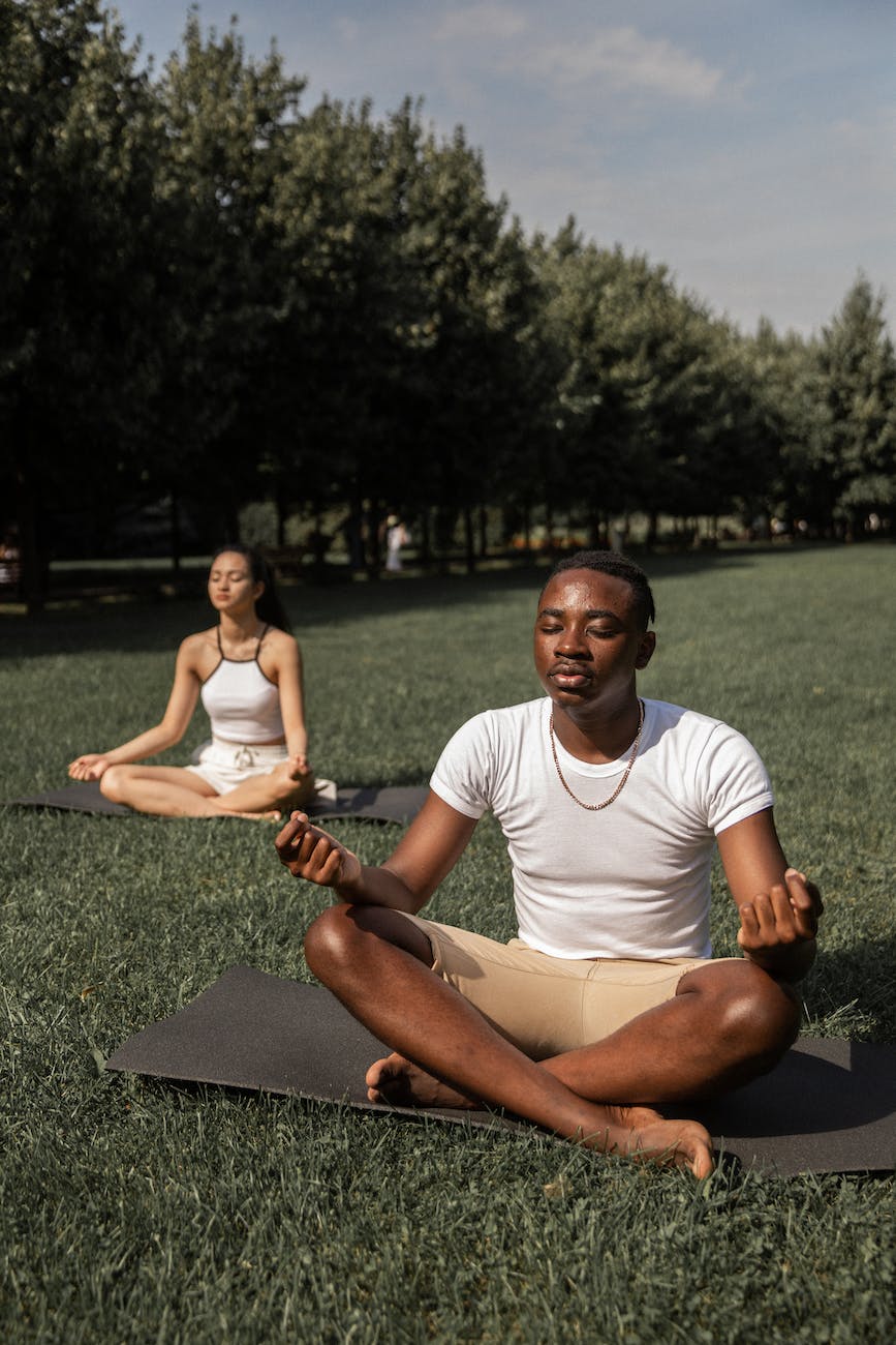 multiethnic couple meditating together in park