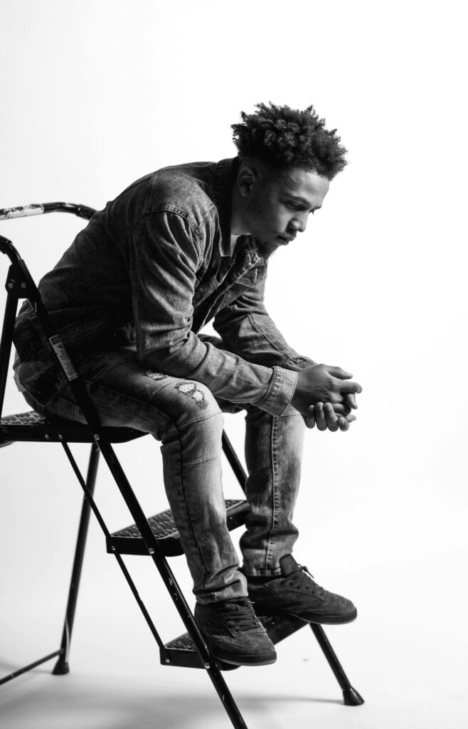 Monochrome photo of a man sitting thoughtfully on a ladder.